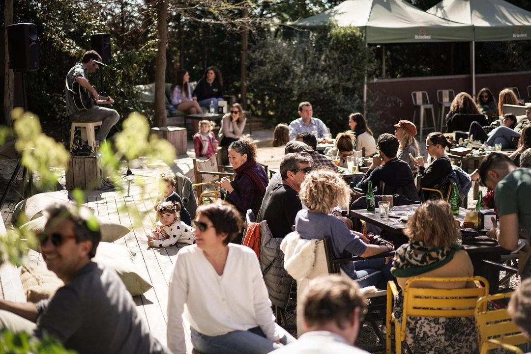 A sunlit outdoor patio crowded with people at a social gathering.